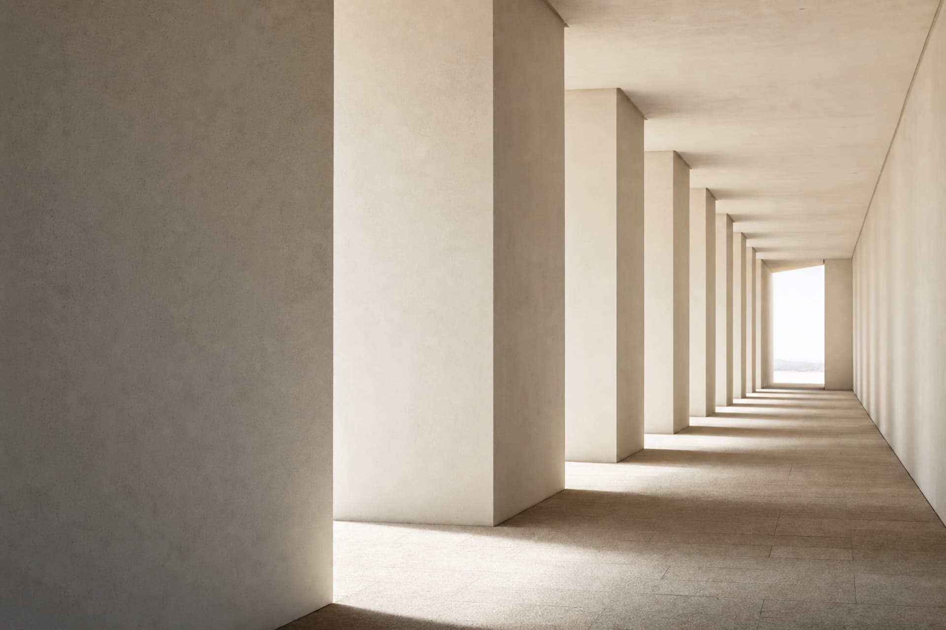 Portique de piliers en enduit clair, le rythme de leurs ombres portées sur un sol de pierre