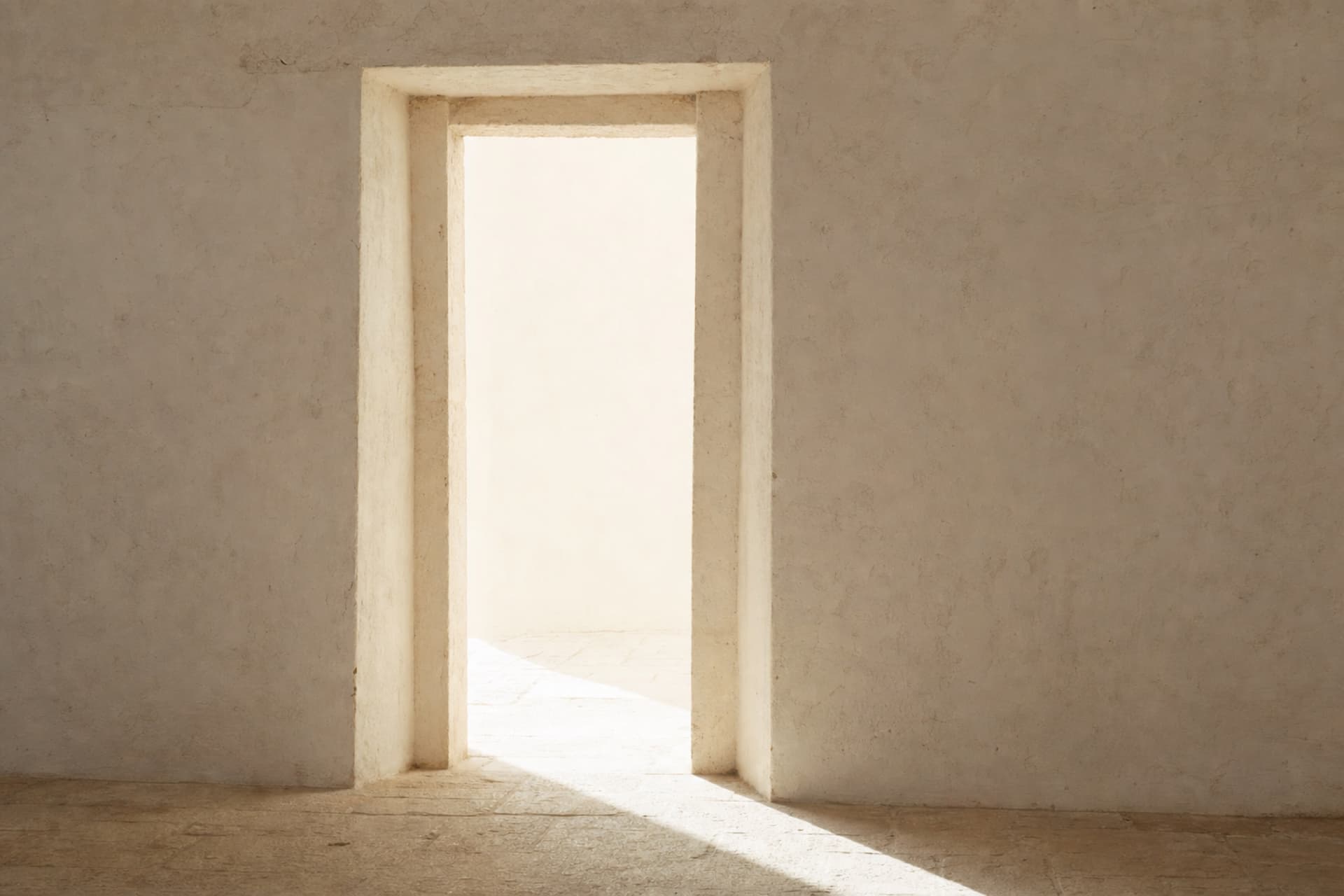Ouverture pratiquée dans un mur de plâtre crème, la lumière du jour se répandant sur le seuil